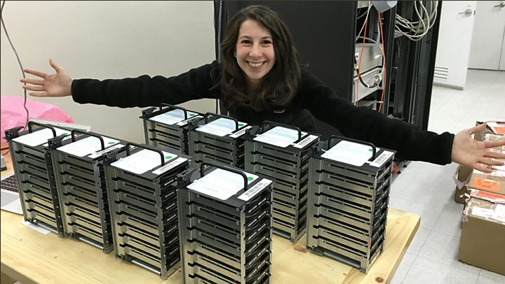 Bouman sitting next to stacks of hard drives holding black hole imaging data.