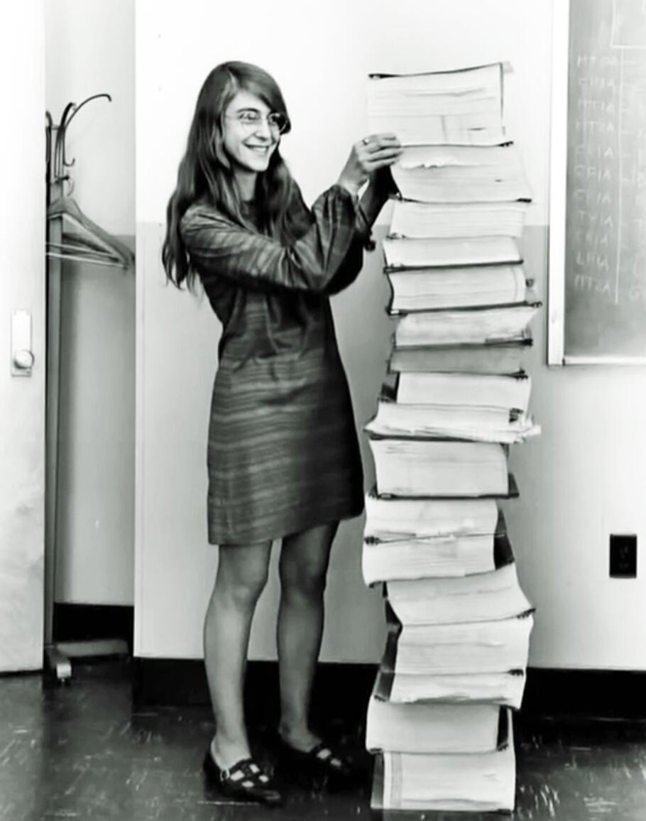 Margaret Hamilton standing next to the listings of the Apollo Guidance Computer source code